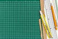 Yellow cutter knife with ruler, pencil and paper sheets on green Royalty Free Stock Photo