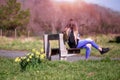 Yellow daffodil grow in a park by a bench, young teenager with long hair looking away from camera, nobody. Warm sunny day, Trees Royalty Free Stock Photo