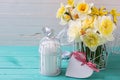 Yellow daffodils flowers, candle in decorative bird cage and heart on turquoise wooden planks against white wall. Royalty Free Stock Photo