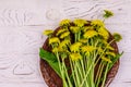 Yellow dandelion flowers in wicker basket on white wooden background. Top view Royalty Free Stock Photo