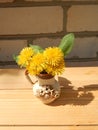 Beautiful yellow dandelions in a vase on the table, spring flowers, clear weather.