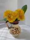 Beautiful yellow dandelions in a vase on the table, spring flowers, clear weather.