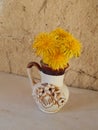 Beautiful yellow dandelions in a vase on the table, spring flowers, clear weather.