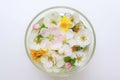 Yellow dandelions and white blooming flowers in a glass bowl with water on a white table Royalty Free Stock Photo