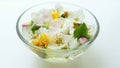 Yellow dandelions, white blooming flowers and green leaves in a glass bowl with water on a white table Royalty Free Stock Photo