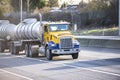 Yellow day cab big rig semi truck transporting liquid cargo in two tank semi trailers running on the multiline interstate highway Royalty Free Stock Photo