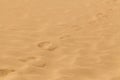 Yellow desert sand with footprints on it.