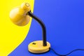 Yellow desk lamp isolated on blue and yellow background