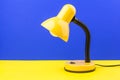 Yellow desk lamp isolated on blue and yellow background