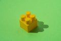 Yellow detail of children`s constructor isolated on green background