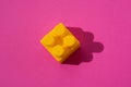 Yellow detail cube of children`s constructor on a pink background