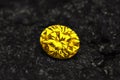 A yellow diamond is sitting on a black rock Royalty Free Stock Photo
