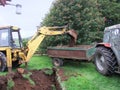 Yellow Digger digging foundations for an extinction to a bungalow with tractor and trailer
