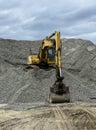 Yellow digger machine on top of a large pile of pebbles and stones Royalty Free Stock Photo