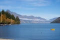 Yellow dinghy and foliage of tall trees on edge of lake Royalty Free Stock Photo