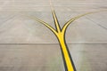 Yellow direction strips fork close up on an airfield runway.