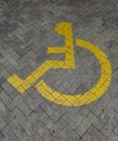 Yellow Disabled Parking Symbol on Brick Pavement Royalty Free Stock Photo