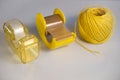 A yellow dispenser of adhesive tape and packaging tape and a roll of packaging cord Royalty Free Stock Photo