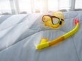 Yellow diving mask and snorkel on white duvet bed background. Royalty Free Stock Photo