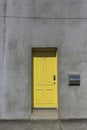 Yellow door in a plain concrete facade.