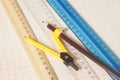 Yellow Drawing compass with black pensil and rulers on graph