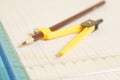 Yellow Drawing compass with pensil and rulers on graph paper.En