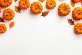 Yellow dried leaves and small orange pumpkins on white background, top view, copy space. Halloween, Thanksgiving holiday concept