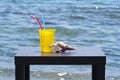 Drinking glass and seashell in fronf of blue sea