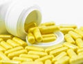 Yellow Drug Capsules spilled from container Royalty Free Stock Photo