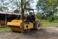 Yellow drum roller machine vehicle parking in the middle of city park