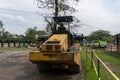 Yellow drum roller machine vehicle parking in the middle of city park