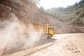 The yellow dump truck working on the dusty mountain road at construction site, a new road construction near Laos-Vietnam border