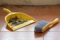 The yellow dustpan and brush are being used. with dust and dirt inside