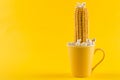 A yellow ear of corn sticking out of a yellow cup, as if growing, popcorn is scattered, on a yellow background, concept Royalty Free Stock Photo