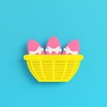 Yellow easter eggs with bow in a wicker basket on bright blue background in pastel colors
