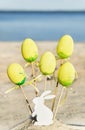 Yellow easter eggs, wooden rabbit are on the beach with sea.