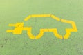 Yellow electric car symbol painted on a green concrete floor, without people Royalty Free Stock Photo