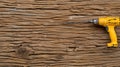 A yellow electric drill lays on a rough brown wooden surface Royalty Free Stock Photo