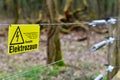 Yellow electric fence warning sign with German text saying `Attention, electric fence` Royalty Free Stock Photo