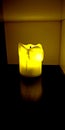 Yellow electric flameless battery powered candle shining in dark cabinet