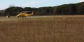 Yellow emergency helicopter parked in a barren dirt field with spontaneous vegetation in tuscany