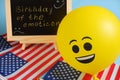 Yellow emoji balloons on the background of the board with the event inscription and American flags. Royalty Free Stock Photo