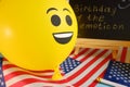 Yellow emoji balloons on the background of the board with the event inscription and American flags. Royalty Free Stock Photo