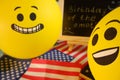 Yellow emoji balloons on the background of the board with the event inscription and American flags. Royalty Free Stock Photo