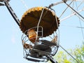 Yellow empty ferris wheel booth with seats and peeling paint on top with rust stains