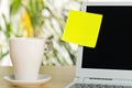 Yellow empty sticky note on laptop screen with white coffee or tea cup with copy space on brown wooden desk in office Royalty Free Stock Photo