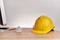 Yellow engineer hat and house on wooden computer table Royalty Free Stock Photo