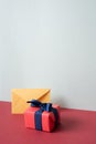 Yellow envelope and pink gift box on red desk. gray wall background Royalty Free Stock Photo