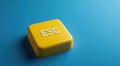 Yellow escape key button on a blue background, symbolizing control and the concept of quitting or exiting situations Royalty Free Stock Photo