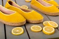 Yellow espadrilles shoes near slices of lemon on wooden background. Close up.